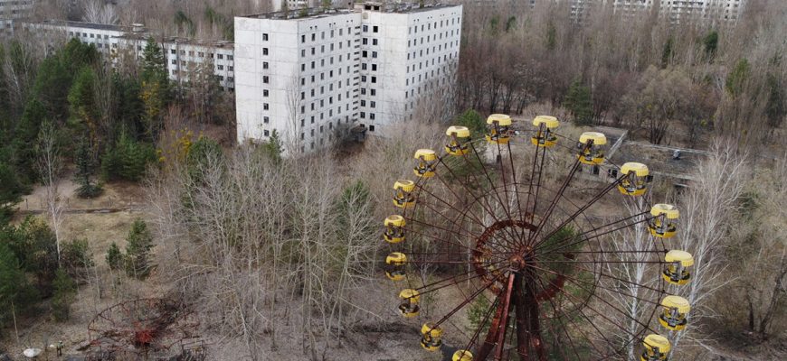35 лет назад произошла огромная трагедия, изменившая жизнь не только сотен тысяч украинцев, но и жителей планеты в целом. Взрыв на 4-ом энергоблоке в апреле 1986 года загрязнил атмосферу радиацией, и последствия человеческой халатности планета ощущает на себе до сих пор. Чернобыль находится всего в 2-х километрах от городка Припять, который на то время подавал огромные надежды и с радостью принимал новых жителей. К сожалению, ему не судьба была стать городом, в котором кипит жизнь: после взрыва более 100 тыс. жителей были эвакуированы, а 30-километровая зона стала зоной отчуждения. Работу ЧАЭС остановили в 2000 году, но полноценная остановка работы энергоблоков может занять еще очень много времени. Саркофаг, построенный над 4-м энергоблоком, полностью достроили в 2019 году и ввели в эксплуатацию. Работы по реконструкции саркофага и остановке работы ЧАЭС продолжаются до сих пор, а туроператоры организовывают экскурсии в зону отчуждения. Много туристов хочет попасть в Чернобыль и посмотреть на все своими глазами. Спустя больше чем 30 лет природа победила цивилизацию и поглотила город. Попав туда, кажется, что здесь всегда был непролазный лес и только заброшенные дома каким-то непонятным образом здесь оказались. Там, где раньше были кафе, кинотеатр, парки с развлечениями - сейчас растут деревья. Дома выглядят устрашающе, а квартиры внутри уже не напоминают уютные помещения, в которых раньше жилы люди. Время, осадки и погода повлияли на состояние квартир - уже нет следа от какого-либо ремонта, все некрасивое и заброшенное. Очень сильно такому внешнему виду домов и квартир в частности помогли мародеры: они вывезли отсюда все ценное (металл, вещи, ценности и все то, чем можно поживиться и на чем заработать денег) и оставили после себя разруху и бардак. Зайдя в любую из квартир, сразу понимаешь, что здесь побывал человек с желанием наживы: все разбросанное, исковерканное, батареи отсутствуют, как и большинство металлических предметов в квартирах. Все лежит вверх дном. Люди, которых насильно эвакуировали из их домов, верили, что когда-то вернутся сюда, но их мечте не суждено было сбыться. Большинство их вещей осталось в квартирах как приманка для людей, желающих поживиться за чужой счет. Когда оказываешься в Припяти, кажется, что только вчера здесь бурлила и кипела жизнь: молодежь гуляла по парку, школьники шли учиться, старики сидели на лавочках и говорили о своем, а сегодня ничего этого здесь нет. Только шум листьев и тоскливое молчание города, который когда-то должен был стать пристанью для спокойной, размеренной и счастливой жизни. Туристы, чтобы попасть в зону отчуждения, проходят строгий досмотр и не могут быть на территории Припяти и Чернобыля в открытой одежде. Также они не могут попасть туда самовольно - пребывание разрешено только в присутствии гида. Находиться здесь можно не более чем 5 дней, но поток туристов просто огромен: после выхода в 2019-м году сериала "Чернобыль" количество желающих попасть сюда и увидеть все своими глазами выросло в несколько раз. Больше 125 тыс. человек посетило зону отчуждения и количество туристов не уменьшается.